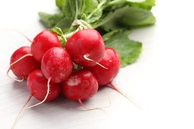Photo of Bunch of fresh radishes on white wooden table, closeup