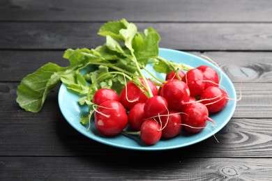 Photo of Many fresh radishes on black wooden table, closeup