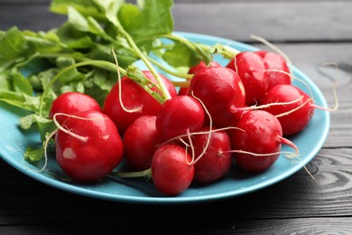 Photo of Many fresh radishes on black wooden table, closeup