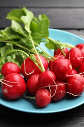 Photo of Many fresh radishes on black wooden table, closeup