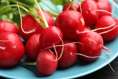 Photo of Many fresh radishes on black wooden table, closeup