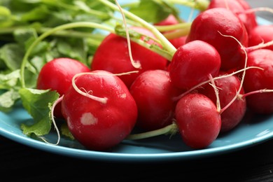 Photo of Many fresh radishes on black table, closeup
