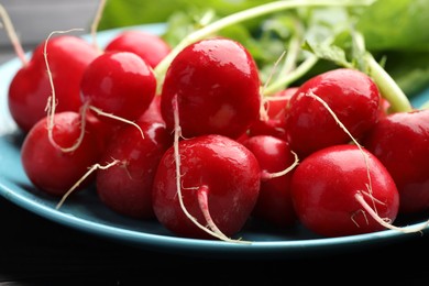 Photo of Many fresh radishes on black table, closeup