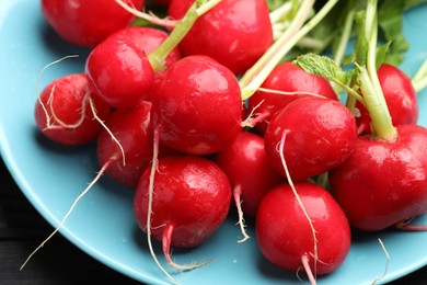 Photo of Many fresh radishes on black table, closeup