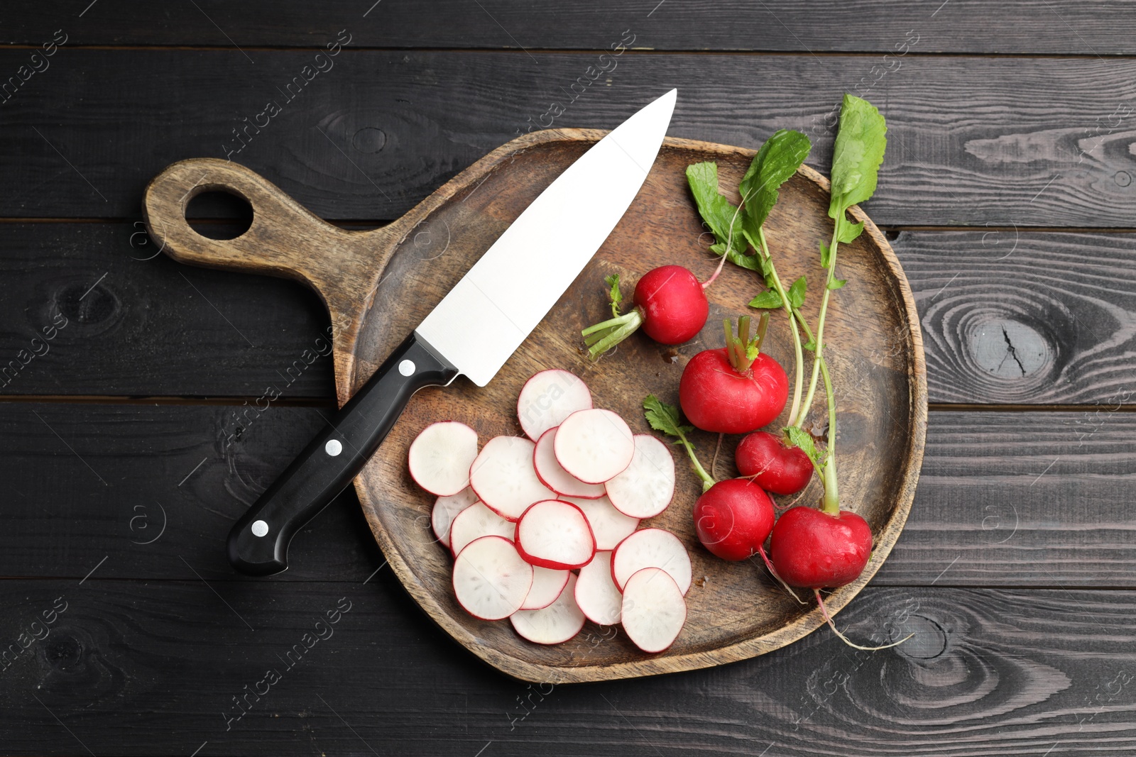 Many fresh radishes and knife on black wooden table, top view Photo of Many fresh radishes and knife on black wooden table, top view