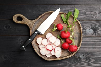 Photo of Many fresh radishes and knife on black wooden table, top view