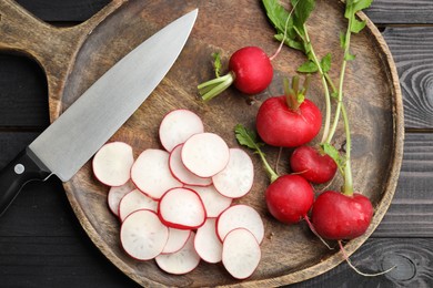 Photo of Many fresh radishes and knife on black wooden table, top view