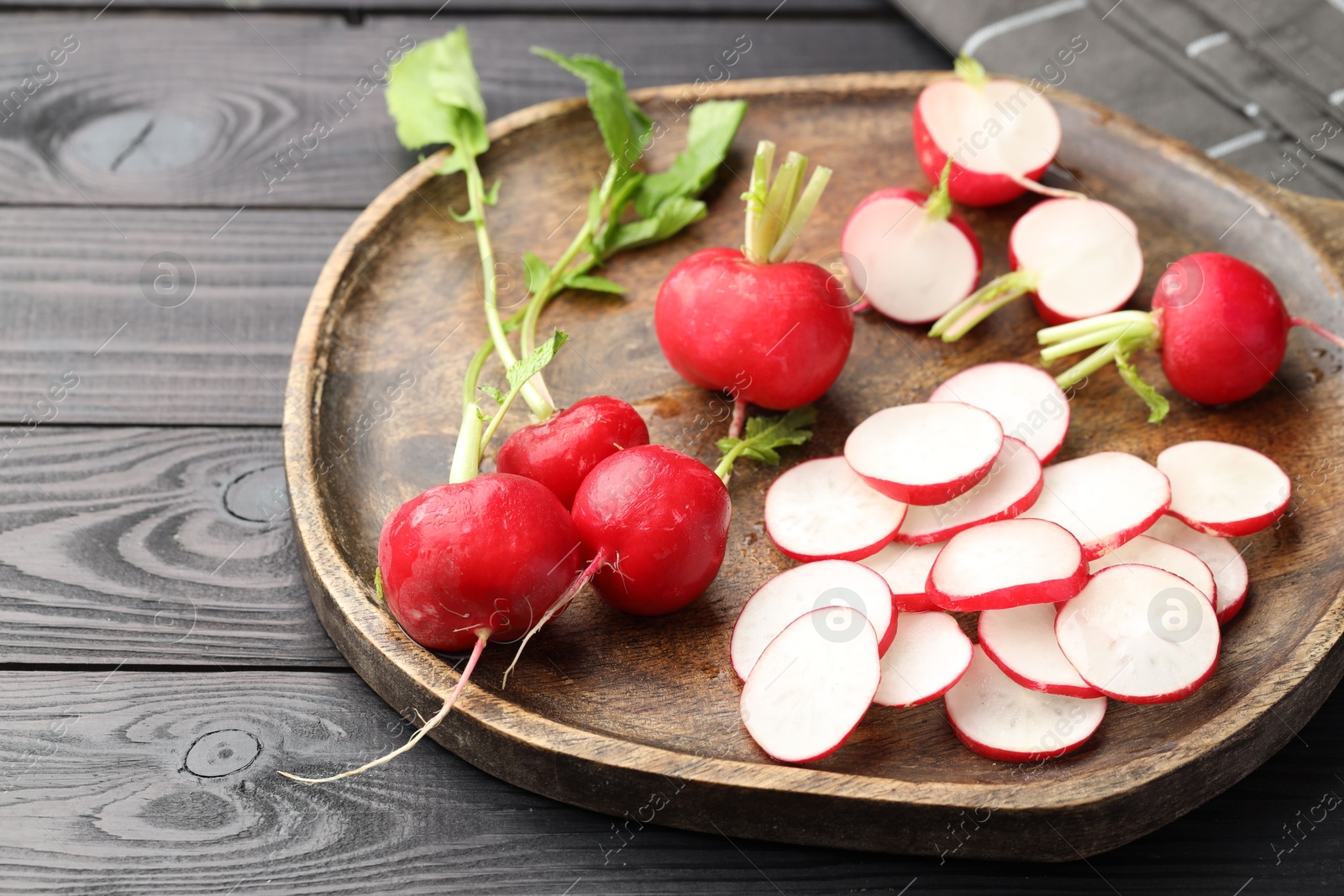Fresh whole and cut radishes on black wooden table, closeup Photo of Fresh whole and cut radishes on black wooden table, closeup