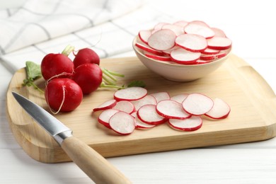 Photo of Many fresh radishes and knife on white wooden table, closeup