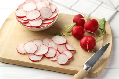 Photo of Many fresh radishes and knife on white wooden table, closeup