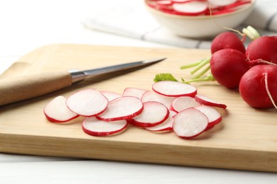 Photo of Many fresh radishes and knife on white table, closeup