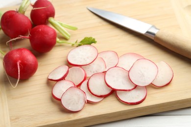 Photo of Many fresh radishes and knife on white table, closeup