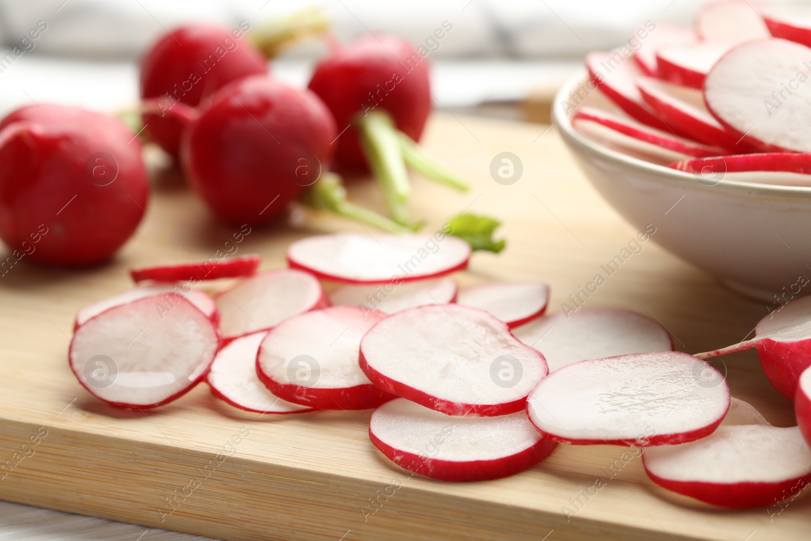 Photo of Fresh whole and cut radishes on table, closeup