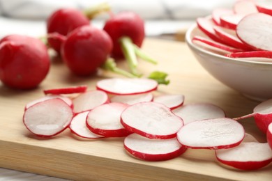 Photo of Fresh whole and cut radishes on table, closeup