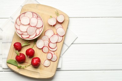 Photo of Fresh whole and cut radishes on white wooden table, top view. Space for text