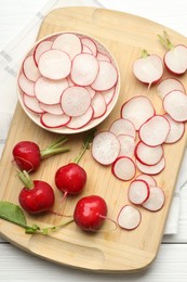 Photo of Fresh whole and cut radishes on white wooden table, top view