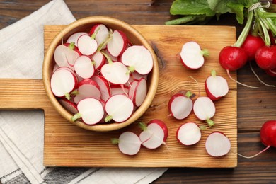 Photo of Fresh cut and whole radishes on wooden table, flat lay