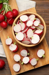 Photo of Fresh cut and whole radishes on wooden table, flat lay