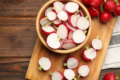 Photo of Fresh cut and whole radishes on wooden table, flat lay. Space for text
