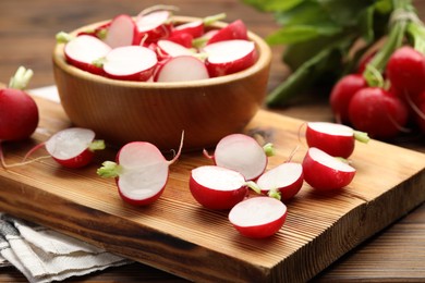 Photo of Fresh cut and whole radishes on wooden table, closeup