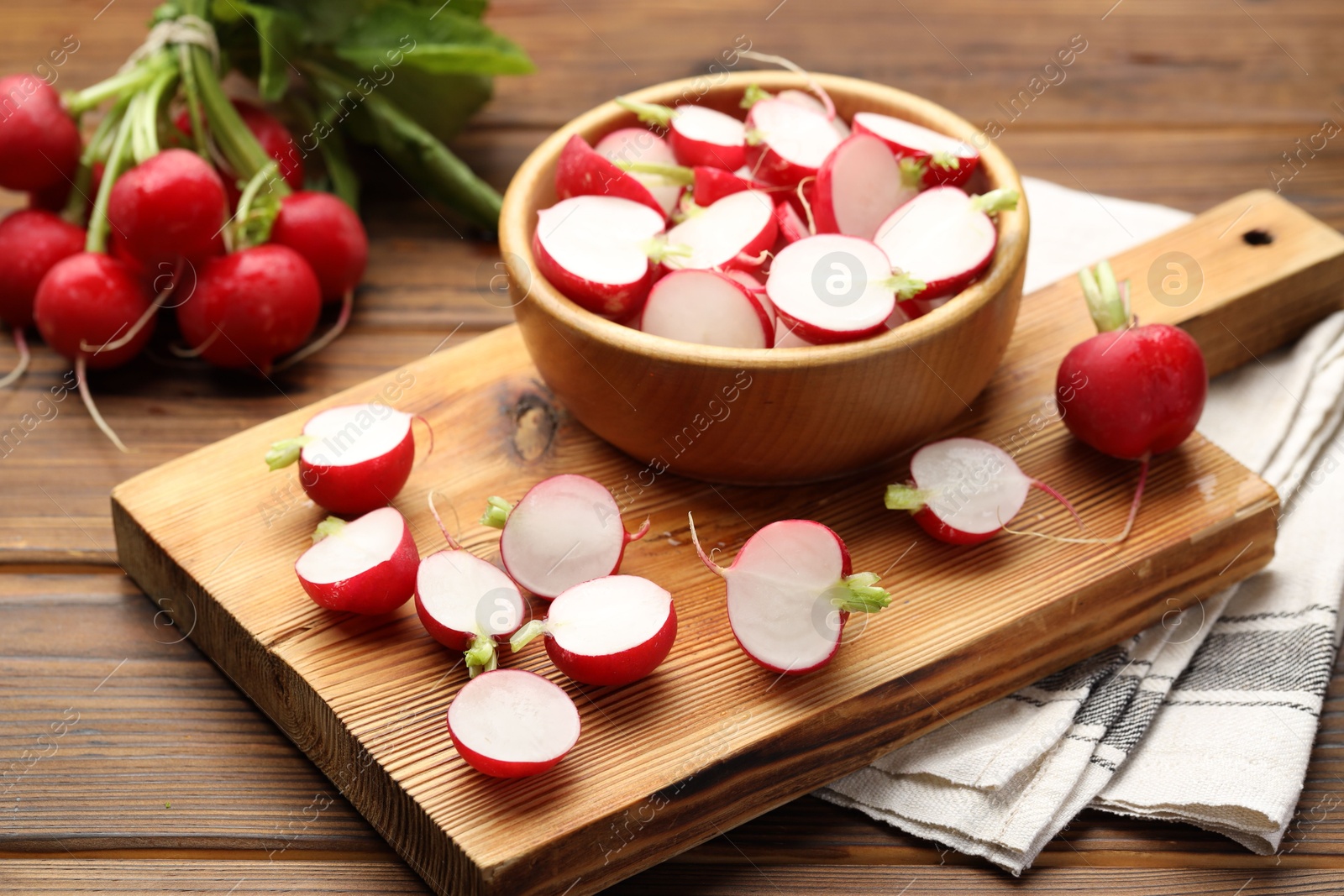 Fresh cut and whole radishes on wooden table, closeup Photo of Fresh cut and whole radishes on wooden table, closeup