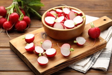 Photo of Fresh cut and whole radishes on wooden table, closeup
