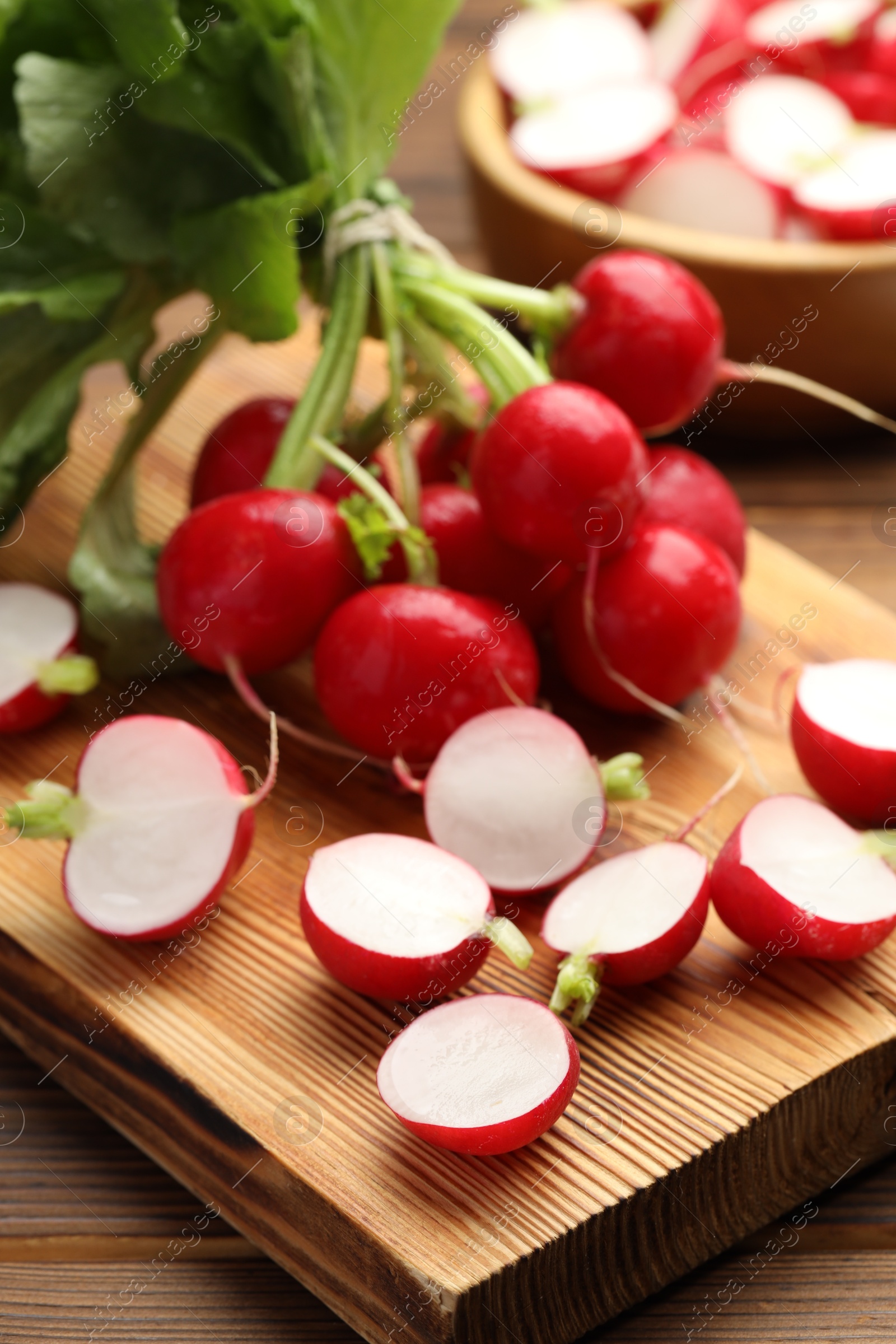 Fresh cut and whole radishes on wooden table, closeup Photo of Fresh cut and whole radishes on wooden table, closeup