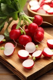 Photo of Fresh cut and whole radishes on wooden table, closeup