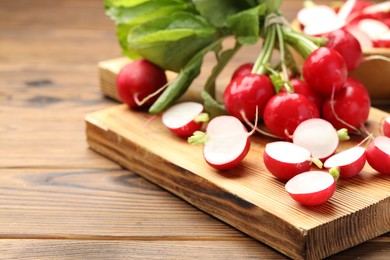 Photo of Fresh cut and whole radishes on wooden table, closeup. Space for text