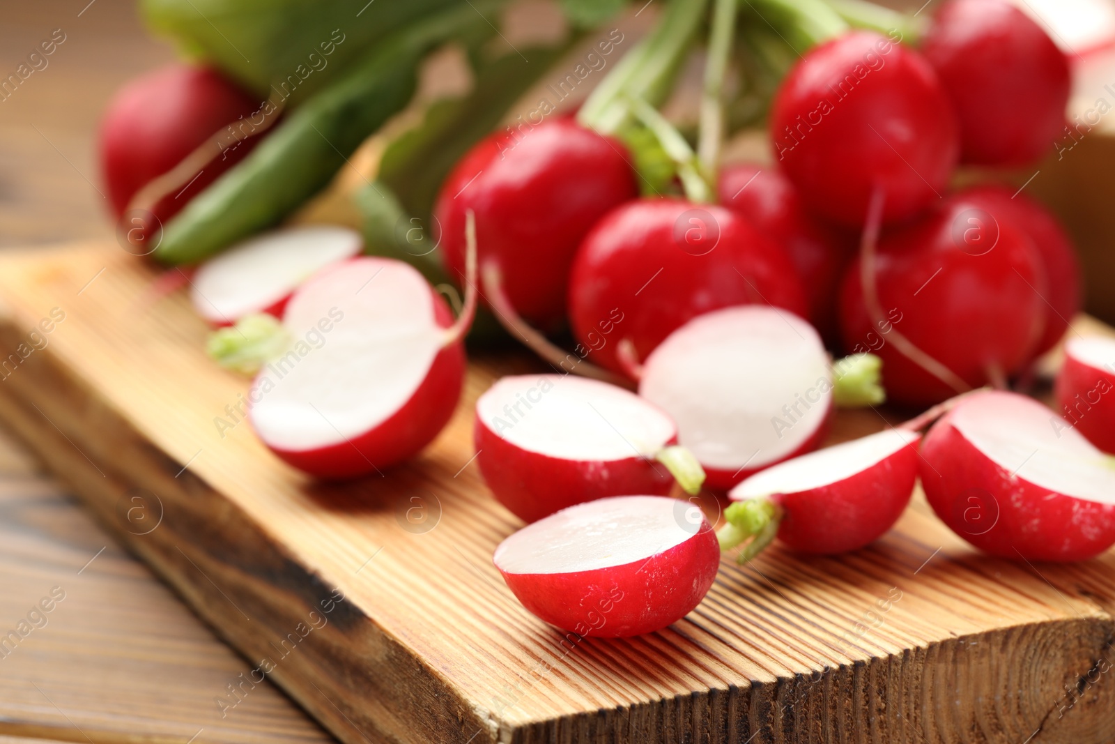 Fresh cut and whole radishes on wooden table, closeup Photo of Fresh cut and whole radishes on wooden table, closeup
