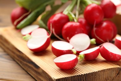 Photo of Fresh cut and whole radishes on wooden table, closeup