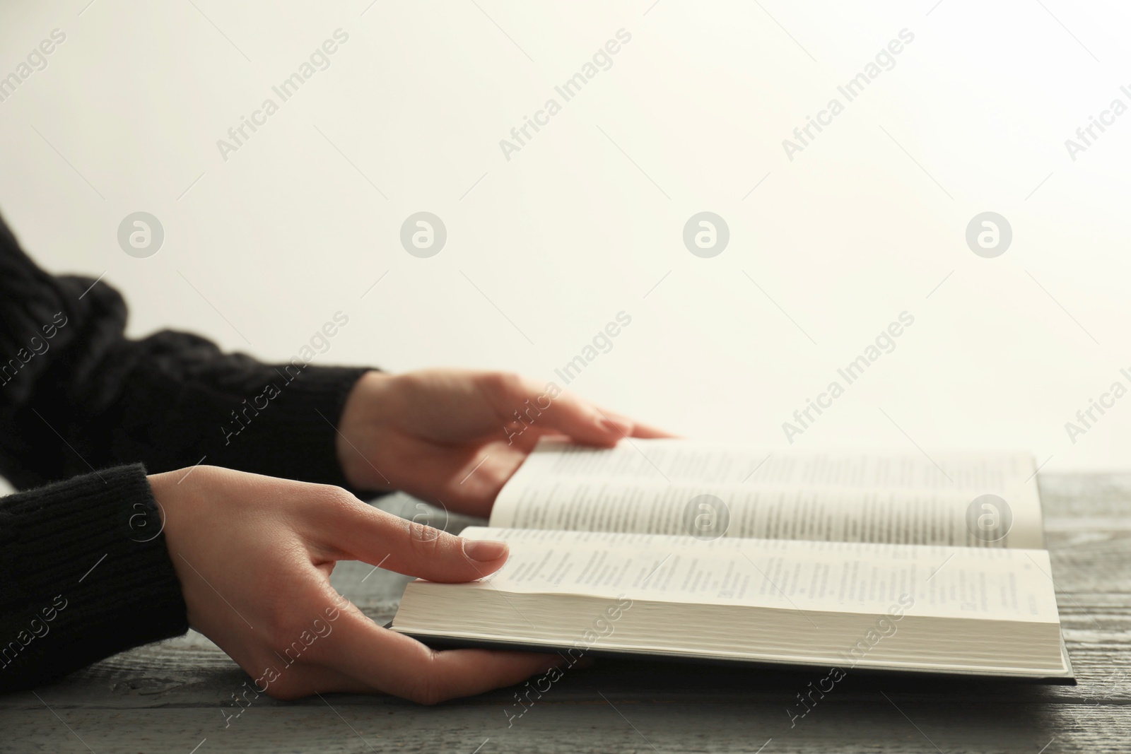 Photo of Woman with open Holy Bible at wooden table, closeup