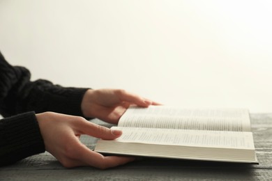 Photo of Woman with open Holy Bible at wooden table, closeup