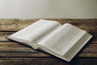 Photo of Open Holy Bible in English language on wooden table