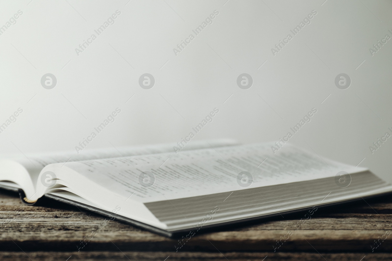 Photo of Open Holy Bible in English language on wooden table, closeup