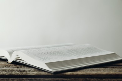 Photo of Open Holy Bible in English language on wooden table, closeup