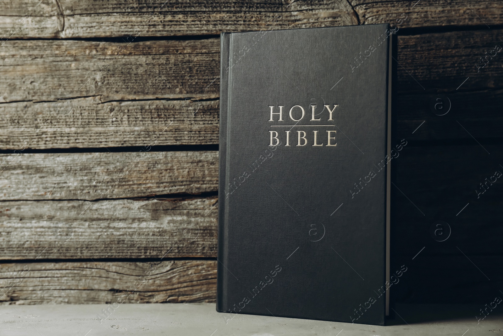 Photo of Hardcover Holy Bible on grey table, space for text