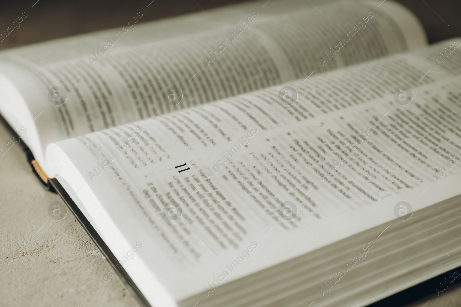 Photo of Open Holy Bible in English language on grey table, closeup