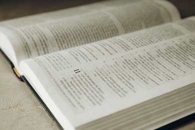 Open Holy Bible in English language on grey table, closeup