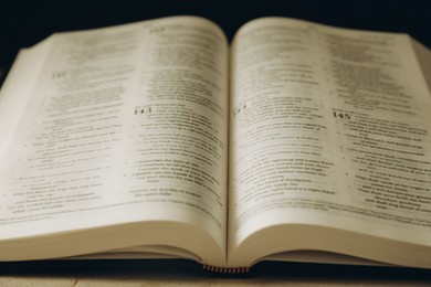 Photo of Open Holy Bible in English language on table, closeup