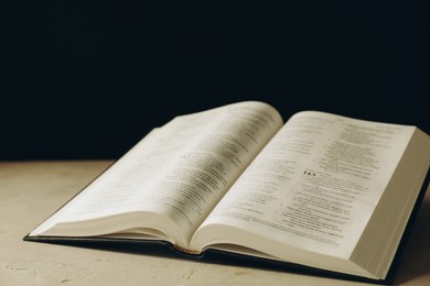 Photo of Open Holy Bible in English language on beige table