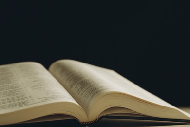 Photo of Open Holy Bible on beige table, closeup