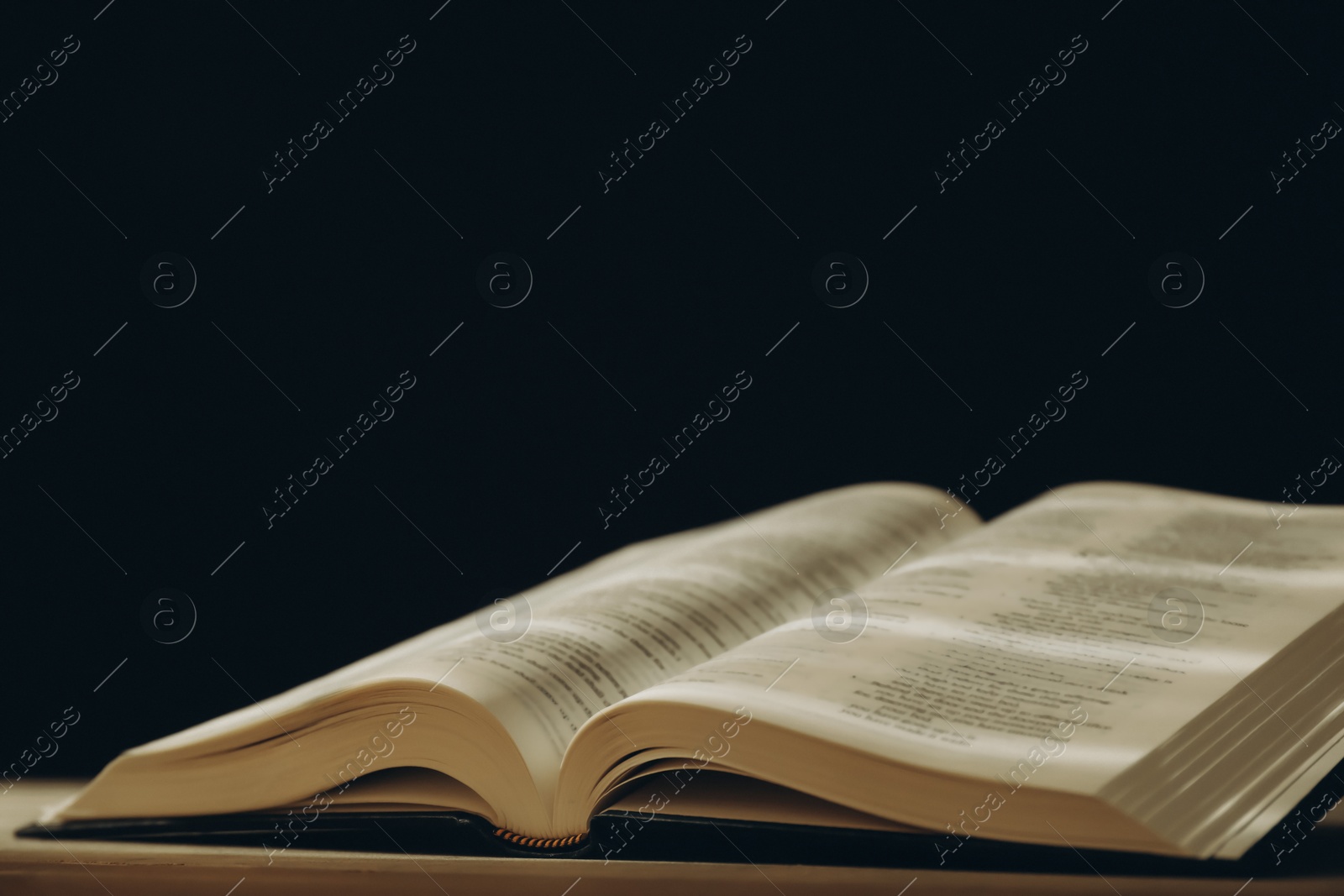 Photo of Open Holy Bible in English language on table, closeup