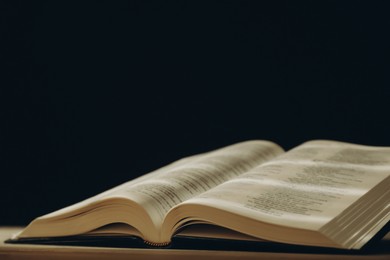 Photo of Open Holy Bible in English language on table, closeup