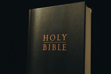 Photo of Hardcover Holy Bible on black background, closeup