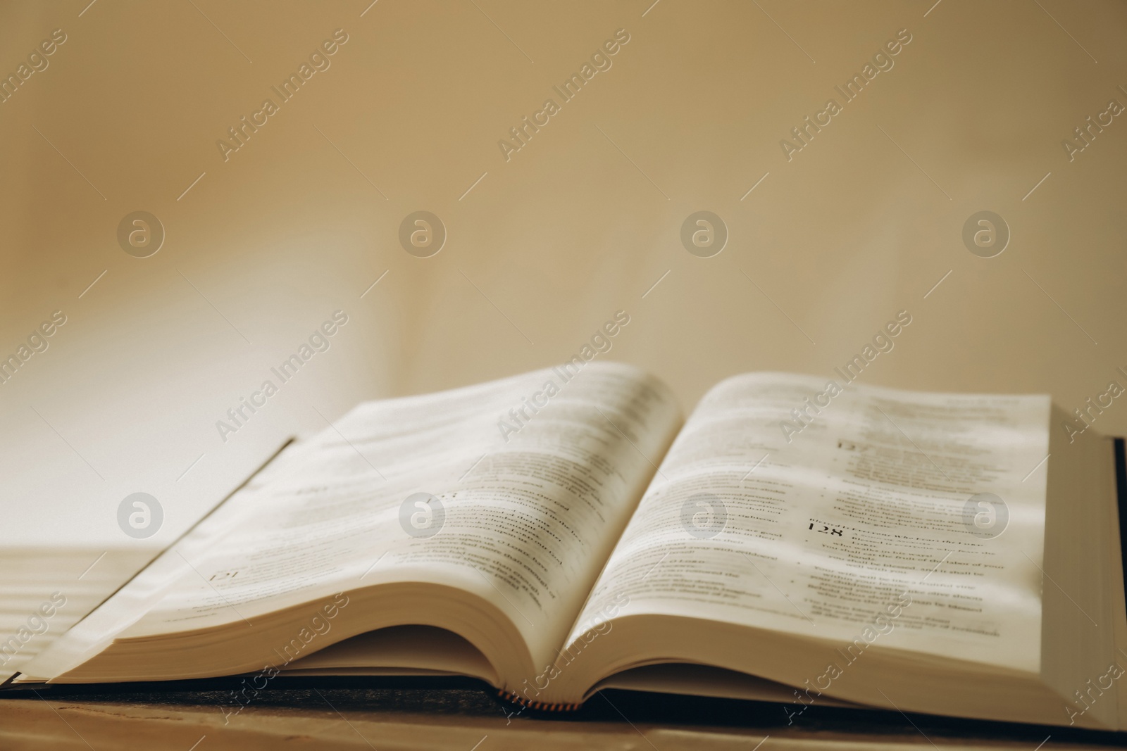 Photo of Open Holy Bible in English language on table, closeup