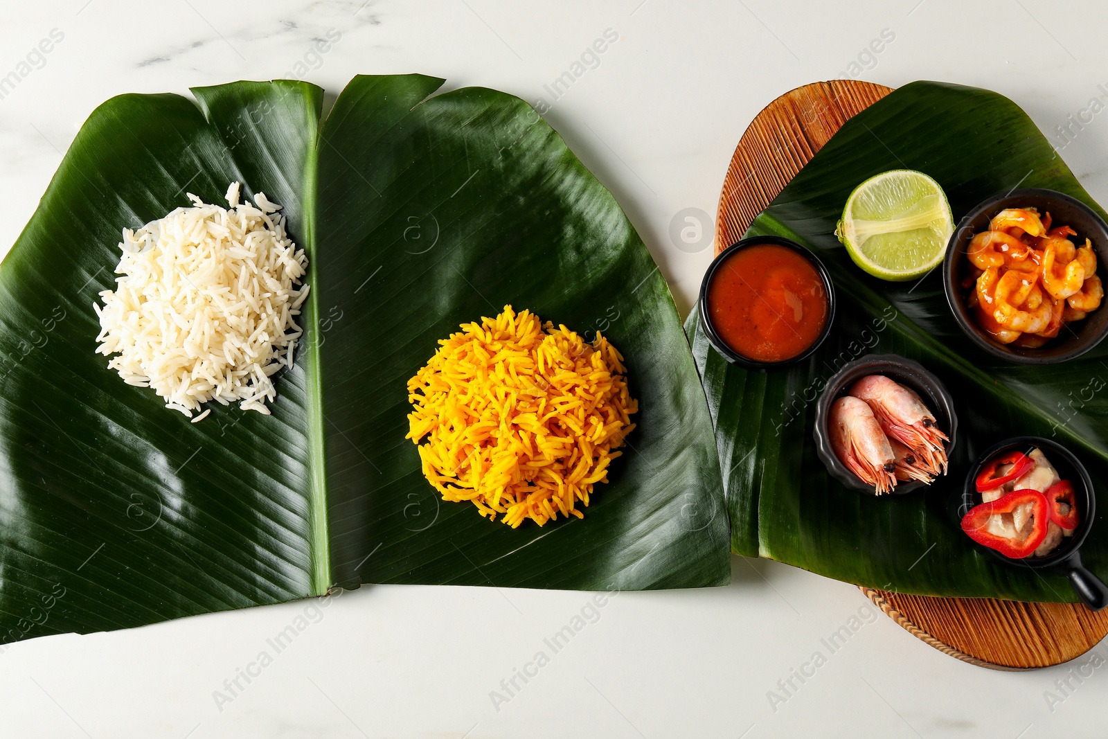 Photo of Cut banana leaves with different food and sauce on white table, flat lay