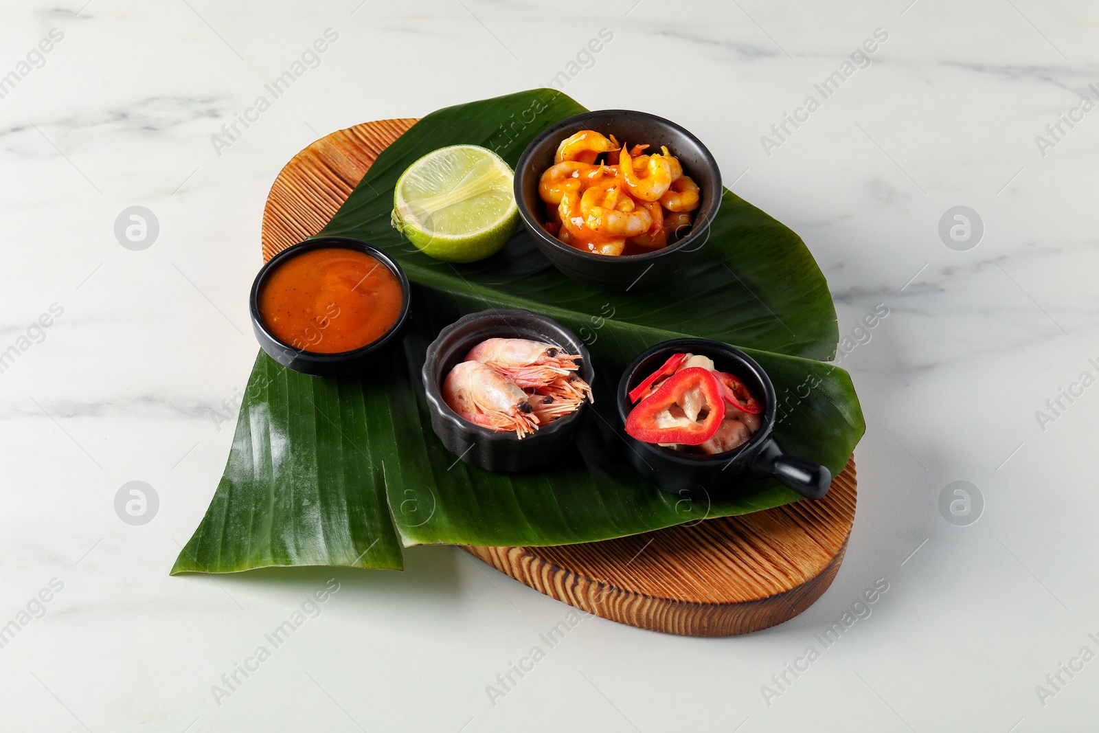 Photo of Cut banana leaf with different food and sauce on white marble table, closeup