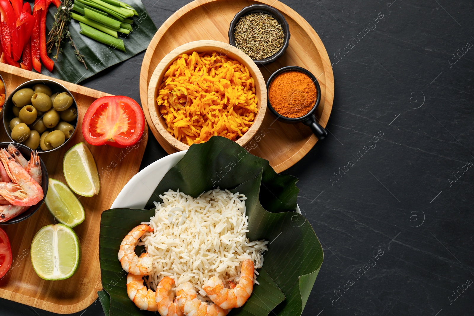 Photo of Cut banana leaves with different food and spices on dark textured table, flat lay. Space for text