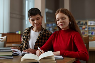 Students studying together at desk in public library